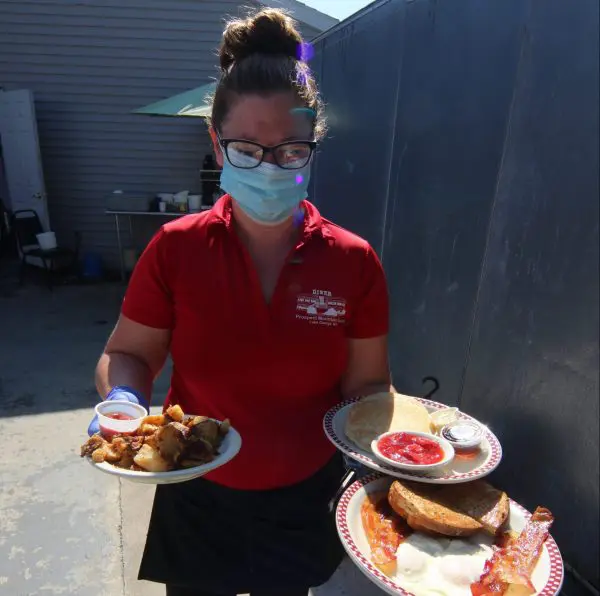 Server bringing food to outdoor dining guests